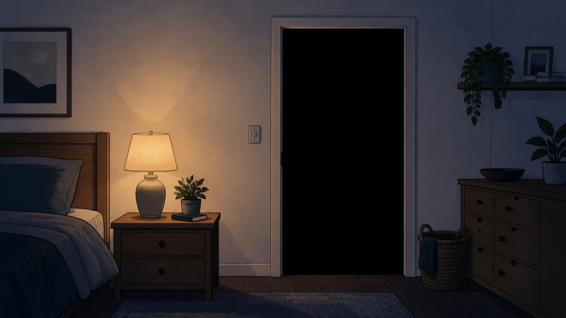 A lamp-lit bedroom facing a pitch-black doorway